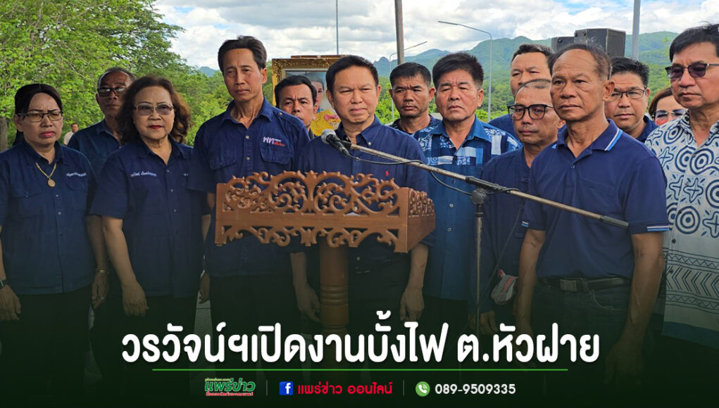 ff กลุ่มคนสวมเสื้อสีน้ำเงินร่วมพิธีเปิดงานบั้งไฟ ต.หัวฝาย โดยมีชายคนหนึ่งยืนพูดที่โพเดียมไม้แกะสลัก