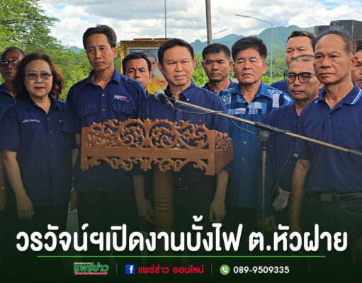 กลุ่มคนสวมเสื้อสีน้ำเงินร่วมพิธีเปิดงานบั้งไฟ ต.หัวฝาย โดยมีชายคนหนึ่งยืนพูดที่โพเดียมไม้แกะสลัก