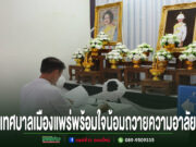 เทศบาลเมืองแพร่พร้อมใจน้อมถวายความอาลัย ร่วมลงนามแสดงความจงรักภักดีและสำนึกในพระกรุณาธิคุณ ชายสวมเสื้อขาวนั่งลงนามถวายความอาลัยหน้าโต๊ะหมู่บูชาที่มีพระบรมฉายาลักษณ์และพานพุ่มดอกไม้สีขาว