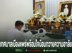 เทศบาลเมืองแพร่พร้อมใจน้อมถวายความอาลัย ร่วมลงนามแสดงความจงรักภักดีและสำนึกในพระกรุณาธิคุณ ชายสวมเสื้อขาวนั่งลงนามถวายความอาลัยหน้าโต๊ะหมู่บูชาที่มีพระบรมฉายาลักษณ์และพานพุ่มดอกไม้สีขาว