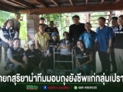 กลุ่มเจ้าหน้าที่ถ่ายภาพร่วมกันขณะมอบถุงยังชีพแก่กลุ่มเปราะบางใต้ถุนบ้าน