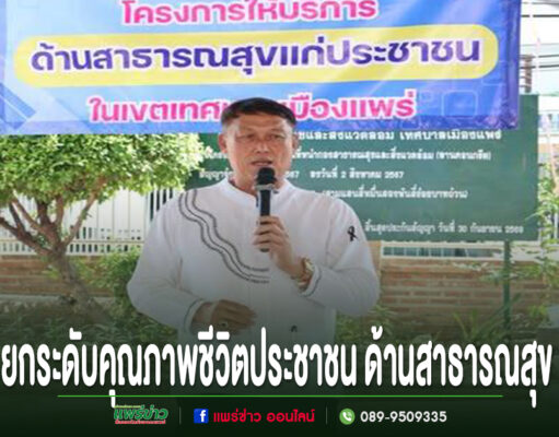ชายสวมเสื้อสีขาวพูดใส่ไมโครโฟน หน้าป้ายโครงการด้านสาธารณสุขแก่ประชาชน