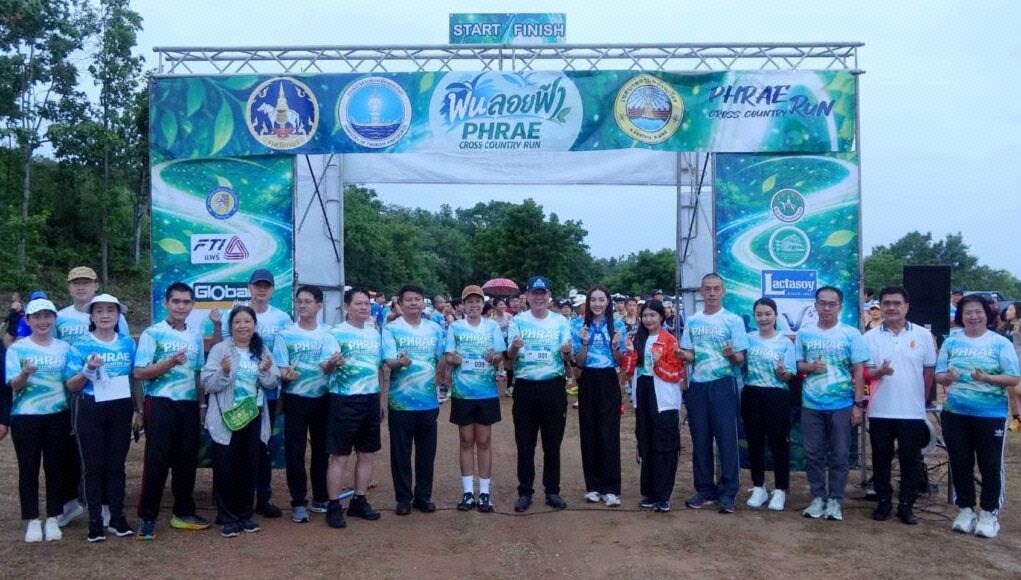 “Phrae Cross Country Run” คึกคัก นักวิ่งทั่วประเทศร่วมวิ่งกลางสายฝน สัมผัสเสน่ห์ถนนลอยฟ้าปูแจ ส่งเสริมท่องเที่ยววิถีใหม่ ใส่ใจสิ่งแวดล้อม กลุ่มคนยืนถ่ายภาพร่วมกันหน้าซุ้มประตูปล่อยตัวงานวิ่ง Phrae Cross Country Run