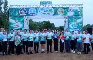 “Phrae Cross Country Run” คึกคัก นักวิ่งทั่วประเทศร่วมวิ่งกลางสายฝน สัมผัสเสน่ห์ถนนลอยฟ้าปูแจ ส่งเสริมท่องเที่ยววิถีใหม่ ใส่ใจสิ่งแวดล้อม กลุ่มคนยืนถ่ายภาพร่วมกันหน้าซุ้มประตูปล่อยตัวงานวิ่ง Phrae Cross Country Run