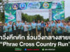 กลุ่มคนสวมเสื้อวิ่งสีฟ้าถ่ายภาพร่วมกันหน้าซุ้มประตูงานวิ่ง Phrae Cross Country Run