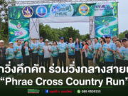 “Phrae Cross Country Run” คึกคัก นักวิ่งทั่วประเทศร่วมวิ่งกลางสายฝน สัมผัสเสน่ห์ถนนลอยฟ้าปูแจ ส่งเสริมท่องเที่ยววิถีใหม่ ใส่ใจสิ่งแวดล้อม กลุ่มคนสวมเสื้อวิ่งสีฟ้าถ่ายภาพร่วมกันหน้าซุ้มประตูงานวิ่ง Phrae Cross Country Run