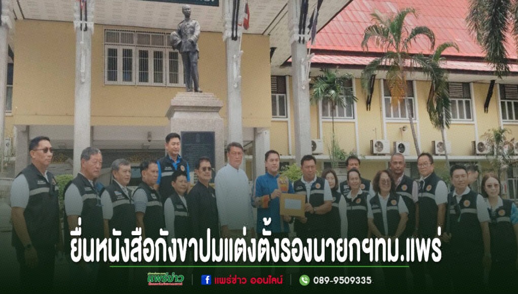 kk กลุ่มคนยืนเรียงแถวหน้าอนุสาวรีย์ ถือเอกสารยื่นหนังสือร้องเรียน พร้อมข้อความภาษาไทยด้านล่าง