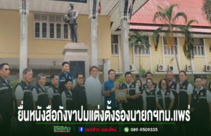 ปมร้อนเทศบาลเมืองแพร่!ประธานสภายื่นหนังสือ ตรวจสอบคุณสมบัติแต่งตั้งรองนายกฯอายุไม่ครบ 35 ปี กลุ่มคนยืนเรียงแถวหน้าอนุสาวรีย์ ถือเอกสารยื่นหนังสือร้องเรียน พร้อมข้อความภาษาไทยด้านล่าง