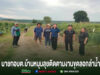 กลุ่มคนยืนถ่ายรูปบนถนนลูกรังกลางทุ่งนา มีข้อความภาษาไทยด้านล่างภาพ