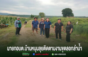 อบต.บ้านหนุนลุยติดตามงานขุดลอกลำน้ำขอบคุณ อบจ.แพร่ สนับสนุนรถแม็คโคร 2 คัน กลุ่มคนยืนถ่ายรูปบนถนนลูกรังกลางทุ่งนา มีข้อความภาษาไทยด้านล่างภาพ