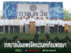 เทศบาลเมืองแพร่จัดขบวนแห่เทียนพรรษา มีผู้คนยืนเรียงแถวบนเวที มีป้ายขนาดใหญ่ด้านหลัง และมีข้อความด้านล่างภาพ