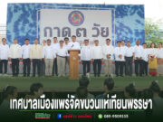 เทศบาลเมืองแพร่จัดขบวนแห่เทียนพรรษา มีผู้คนยืนเรียงแถวบนเวที มีป้ายขนาดใหญ่ด้านหลัง และมีข้อความด้านล่างภาพ