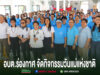 กลุ่มคนสวมเสื้อสีฟ้าและขาวถ่ายรูปร่วมกันในอาคาร พร้อมข้อความภาษาไทยด้านล่าง