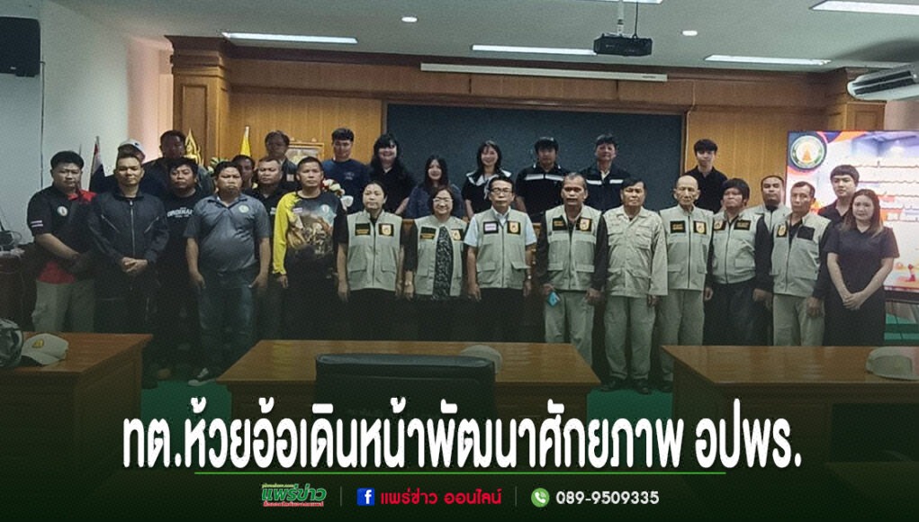 kk กลุ่มคนยืนถ่ายภาพร่วมกันในห้องประชุม มีข้อความภาษาไทยด้านล่างภาพ