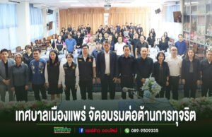 เทศบาลเมืองแพร่จัดอบรมเสริมสร้างคุณธรรม จริยธรรม การป้องกันและการต่อต้านการทุจริต กลุ่มคนยืนถ่ายรูปร่วมกันในห้องประชุม มีข้อความภาษาไทยด้านล่างว่า เทศบาลเมืองแพร่ จัดอบรมต่อต้านการทุจริต
