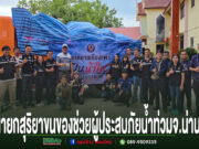 กลุ่มคนยืนถ่ายรูปหน้าขบวนรถบรรทุกสิ่งของช่วยเหลือผู้ประสบภัยน้ำท่วมจังหวัดน่าน