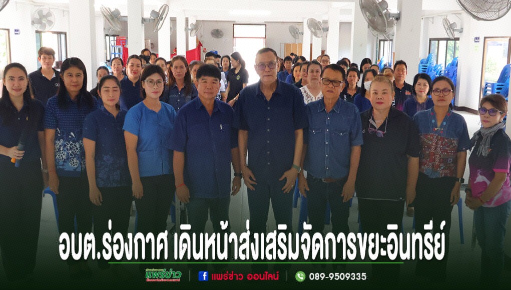 kk กลุ่มคนยืนเรียงแถวถ่ายรูปหมู่ในห้องประชุม มีข้อความภาษาไทยด้านล่างภาพ