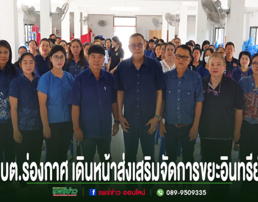 กลุ่มคนยืนเรียงแถวถ่ายรูปหมู่ในห้องประชุม มีข้อความภาษาไทยด้านล่างภาพ