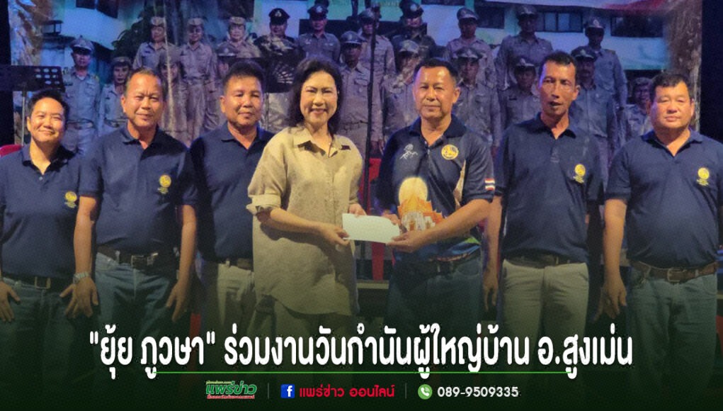 kk กลุ่มคนยืนเรียงแถวหน้ากระดานบนเวที โดยมีหญิงสาวสวมเสื้อสีครีมยื่นซองจดหมายให้ชายสวมเสื้อโปโลสีน้ำเงินด้านข้าง
