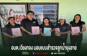 อบต.เวียงทอง มอบแบบสำรวจลูกน้ำยุงลายให้แก่โรงพยาบาลส่งเสริมสุขภาพตำบล 2 แห่ง กลุ่มคน 5 คนยืนถือสมุดรายงานหน้าป้ายประชาสัมพันธ์ อบต.เวียงทอง มอบแบบสำรวจลูกน้ำยุงลาย