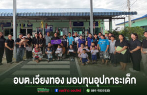 กลุ่มคนร่วมถ่ายภาพหมู่หน้าอาคาร อบต.เวียงทอง พร้อมข้อความมอบทุนอุปการะเด็ก ด้านล่างภาพ