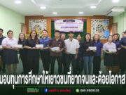 กลุ่มคนยืนเรียงแถวรับทุนการศึกษาในห้องประชุม มีข้อความภาษาไทยด้านล่างภาพ