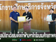 ภาพพิธีมอบเกียรติบัตร ณ สำนักงานศึกษาธิการจังหวัดแพร่ มีผู้ร่วมงาน 3 คนยืนหน้าฉากหลังไม้