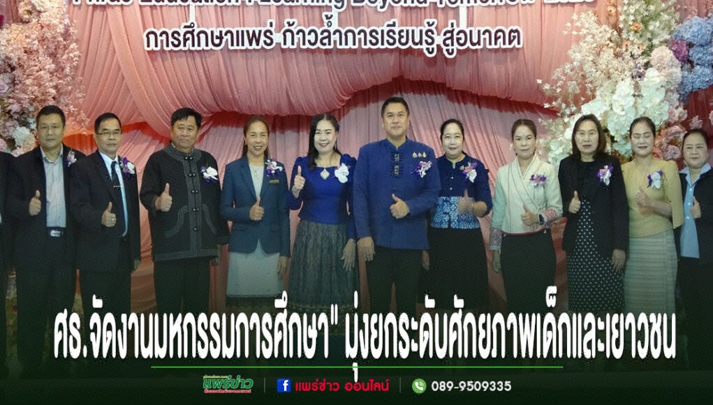 kk กลุ่มคนยืนเรียงแถวหน้าเวทีที่มีป้ายภาษาไทยและภาษาอังกฤษ พร้อมข้อความภาษาไทยด้านล่างภาพ