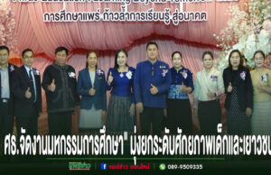 กลุ่มคนยืนเรียงแถวหน้าเวทีที่มีป้ายภาษาไทยและภาษาอังกฤษ พร้อมข้อความภาษาไทยด้านล่างภาพ