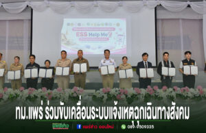 เทศบาลเมืองแพร่ ร่วมขับเคลื่อนระบบแจ้งเหตุฉุกเฉินทางสังคม ESS Help Me สร้างความปลอดภัยให้ประชาชน กลุ่มคนยืนเรียงแถวถือเอกสารความร่วมมือระบบแจ้งเหตุฉุกเฉินทางสังคม ESS Help Me บนเวทีที่มีดอกไม้ประดับด้านหน้า
